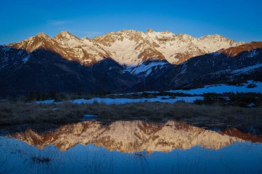 Pyrenees dağlarının üzerinde gün batımı gölün sularındaki tepelerin yansımasıyla yüksek kaliteli 4K görüntü