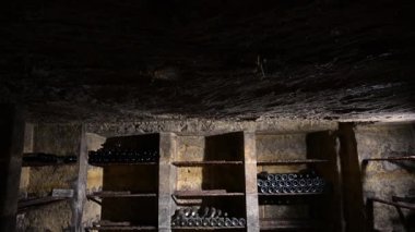 Yaşlı Şarap Şişeleri Deposu Karanlık Kırsal Kiler Bodrumunda, Yalancı Şarap Şişeleri Yığını Kirli ve Toz kaplı, Yaşlanan Şarap Süreci. Yüksek kalite 4k görüntü