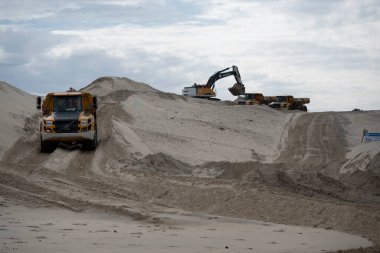 Ağır makineler aktif olarak Biscarosse sahilindeki kum tepecikleri üzerinde çalışıyor. Bulutlu bir gökyüzünün altında Atlantik Okyanusu 'nun yakınındaki manzarayı hazırlıyorlar..