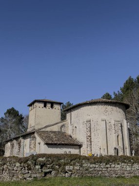 Eglise Saint Pierre, Mons, Gironde, Fransa 'da berrak mavi gökyüzünün altında sakin bir mezarlıkla çevrili ortaçağ mimarisine ev sahipliği yapıyor..
