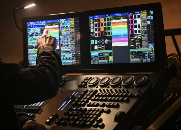 A skilled technician adjusts lighting settings on a digital control board, contributing to the electrifying ambiance of a live concert at a popular venue.