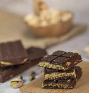 Gurme çikolata ve çıtır çıtır şam fıstığı parçaları ahşap bir tahtada güzelce sunuluyor. Dubais 'in mutfak sahnesinde harika bir ikram oluyor..