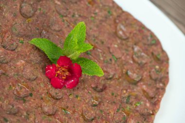 Kebbe naye, zengin bir mutfak deneyimi için tasarlanmış bulgur, soğan, nane ve baharatla karıştırılmış ince doğranmış çiğ et içeren beyaz bir tabakta sergileniyor..