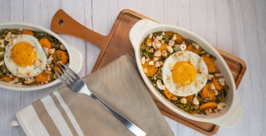 Recipe for kale, carrot and garlic poellee, chopped hazelnuts, cashews and almonds, and fried egg with toasted garlic bread and olive oil