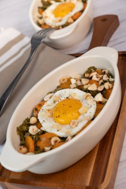 Recipe for kale, carrot and garlic poellee, chopped hazelnuts, cashews and almonds, and fried egg with toasted garlic bread and olive oil