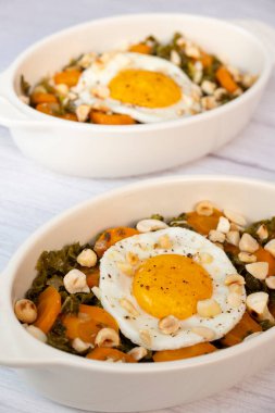 Recipe for kale, carrot and garlic poellee, chopped hazelnuts, cashews and almonds, and fried egg with toasted garlic bread and olive oil