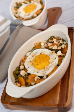 Recipe for kale, carrot and garlic poellee, chopped hazelnuts, cashews and almonds, and fried egg with toasted garlic bread and olive oil