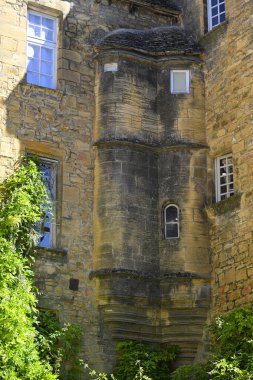 Ziyaretçiler, Sarlat, Dordogne 'daki çarpıcı ortaçağ mimarisine hayret ediyor. Karakteristik taş binaları ve açık mavi gökyüzü altındaki karmaşık ayrıntılarıyla..