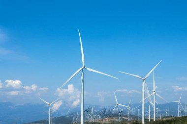 Arka planda temiz mavi gökyüzü olan rüzgar türbinleri. Modern rüzgar jeneratörleri ile yenilenebilir enerji manzarası. Sürdürülebilirlik, temiz enerji ve çevre teknolojisi ile ilgili kavramlar için ideal