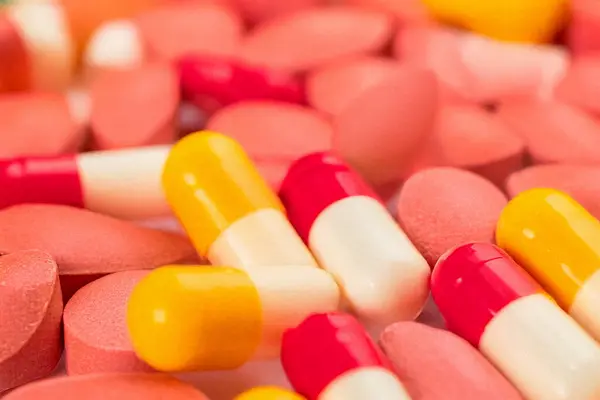 Kabaran ilaç paketleri, ilaç şişeleri ve temiz bir arkaplanda renkli kapsüller. Sağlık, ilaç, tedavi ve refahı temsil eden tıbbi ve ilaç konsepti. Sağlık hizmetleri yayınları, eczane internet siteleri ve sağlık hizmetleri için ideal