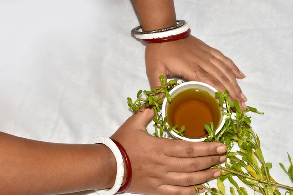 Indian woman takes herbal healing tea made from Brahmi or Bacopa monnieri on a white background. A high angle shot with Selective focus.