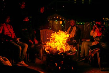 Darjeeling, Batı Bengal; 28 Aralık 2019: Karanlığın içinde turistik kampta kamp ateşi ve turistler eğleniyor. Ateş ve ateş siyaha kıvılcım saçıyor. Ateşe odaklan.