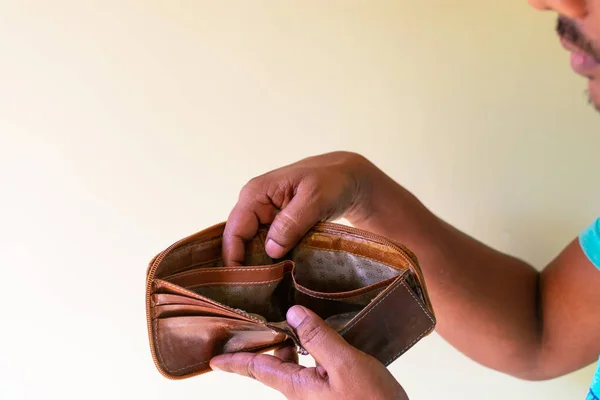 Man hand open an empty wallet on white background. Concept of bankruptcy and insolvency. Selective focus on wallet.