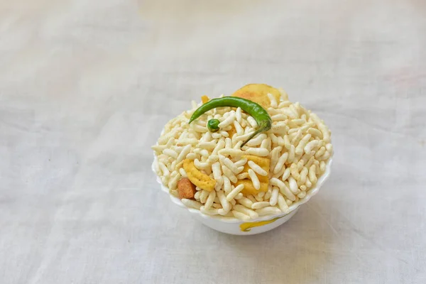 stock image Top view of Murmura spicy puffed rice, Jhal Muri, Borugulu and green chilliin a bowl on white background, in Kolkata, West Bengal, India. is a traditional home made Vegan mid-morning snack or cereal breakfast, Indian street food.