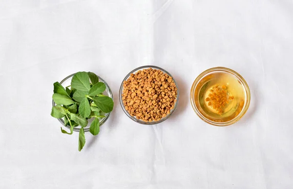 stock image Top view of fenugreek leaves with seeds and oil over white background. Concept of Indian ayurvedic medicine for blood suger, and damage hair and hairfall control.