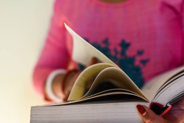 Üniversite kütüphanesinde kitap okuyan tanınmayan bir kadın. Seçici odaklanma, kitap kapanışı.