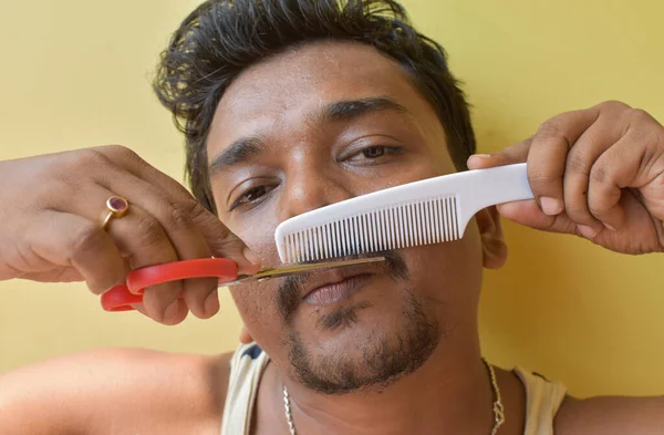 노란색 배경을 깨끗하게 위하여 수염을 빗질을 인디언 젊은이의 선택적 — 스톡 사진