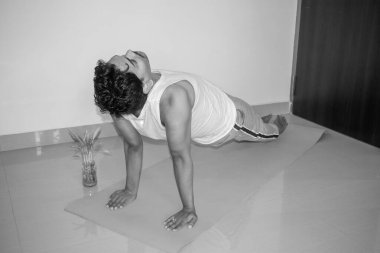 Hintli bir adam spor salonunda yoga pozu veriyor. Hintli adam yoga yapıyor. Yogi konsepti. Yan görünüş ve siyah beyaz resim. Seçici odak.