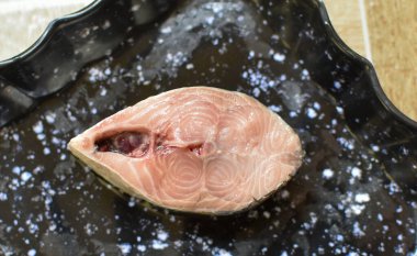 Bir dilimlenmiş Hilsa balığı parçası ve siyah tabakta yumurta. Boşluğu kopyala ve balığa odaklan.