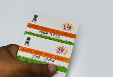 Batı Bengal, Hindistan, 21 Haziran 2024: Hindistan 'ın Aadhaar kartı kimliği beyaz zemin üzerinde seçici odak ve kopyalama alanı ile el ele tutuştu.