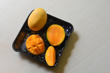 Güneydoğu Asya meyveleri, taze kirpi stili mango hazırlığı, siyah tabakta küp ve parçalar, beyaz arka planda izole edilmiş. Organik yiyecekler.