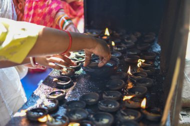 Tapınakta yanmış kil gaz lambaları. Hindu tapınağında geleneksel adak. Kadın eline ve diya 'ya odaklan..