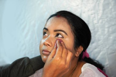 Törenden önce saç stili ve düğün makyajıyla güzel bir Hintli gelin. Sanatçının makyaj malzemeleriyle düğün hazırlığı.