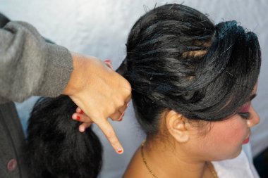 Gelin hazırlığı. Saç şekillendirme süreci kahverengi saçlı kadın, kenar görüşlü uzun saç, toplanmış saç stili, kuaförde stil. Usta görünmez saç tokalarıyla alt saç demetini düzeltir..