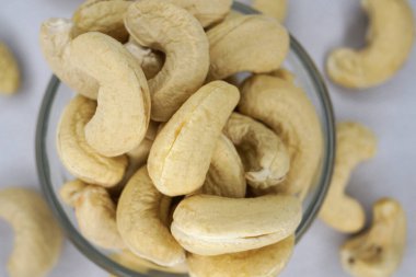 Tabakta çiğ kaju fıstığı ya da beyaz arka planda çuval bezi. Seçici odaklanma. Sağlıklı vejetaryen atıştırmalığı, anakaryum batısı.