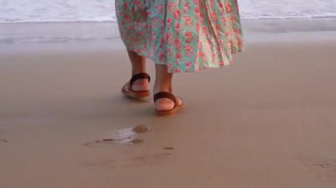 Sabahları kumsalda yürürken bir dişinin çıplak ayaklarına yakın çekim. Seyahat ve tatil kavramı.