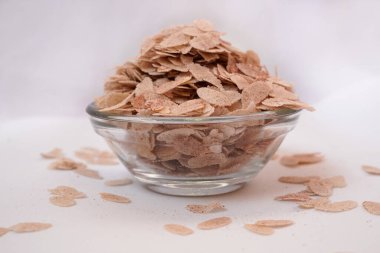 Organic Flattened rice (Oryza Sativa) or Poha in a glass bowl. Isolated on a white background. Side View and selective focus. clipart