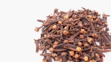Beyaz arka planda Hint kurutulmuş karanfil baharatı damlaları var. Kuru aromatik çiçek tomurcukları, kasede çiçekler. Hint lezzetli karanfilleri baharatlar.