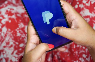 Batı Bengal, Hindistan - 16 Mayıs 2025: Kadın cep telefonunda maaş uygulaması açıyor. PayPal ülkeler arasında en popüler iletişim ve para gönderme yöntemi