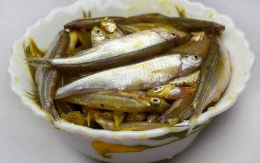 Erimiş. Beyaz arka planda beyaz bir kasede taze çiğ küçük balık. Bir kase küçük balık, kızartmadan önce, seçici odak, üst görüş