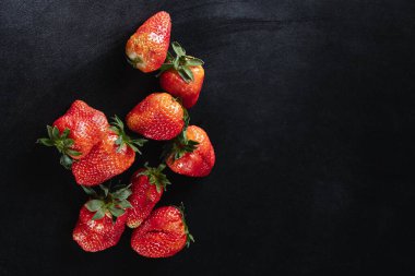 Birkaç sulu olgun çilek siyah arka planda izole edilmiş.