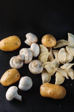 Mantarlı hamur tatlısı ve siyah arka planda patates.