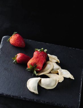 Siyah arka planda sulu çilekli çiğ hamur köftesi.