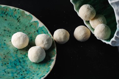 Siyah arka planda hazır peynirli krep topları.