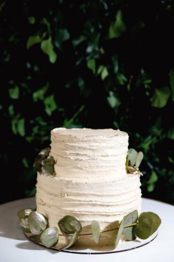 Yaprakların yeşil arka planında beyaz düğün pastası