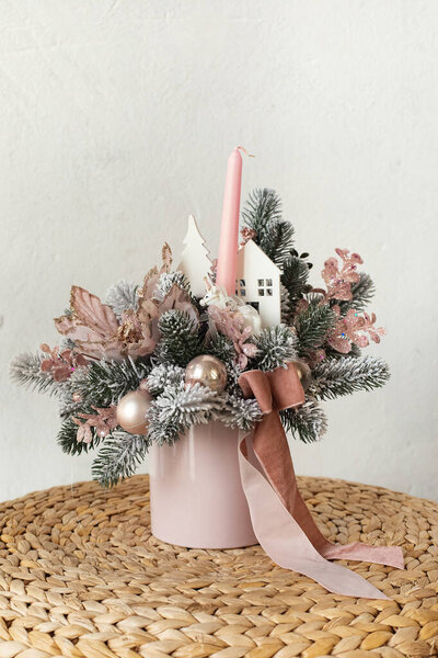 Christmas floral composition of fir branches, candles, and pink ribbon for a gift. New Year's decor for the interior