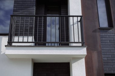 Kulübenin arka planındaki balkonun metal siyah korkuluğu..