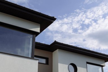 Park ve mavi gökyüzünün arka planında panoramik pencereleri olan modern beyaz kulübeler.