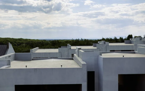 Şehir dışındaki bir parkta, ormanın ve mavi gökyüzünün arka planına karşı modern bir kasaba inşaatı..