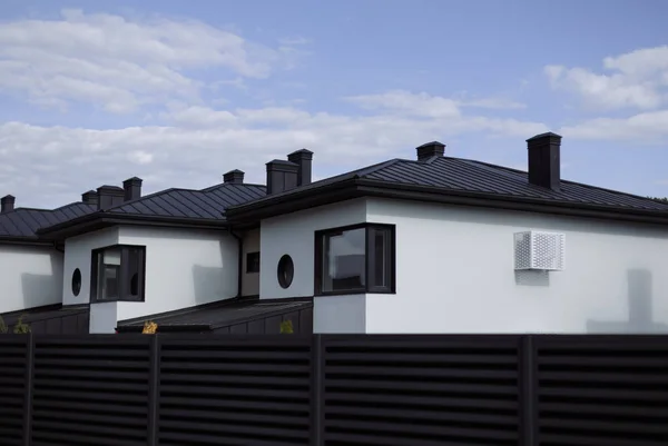 Mavi gökyüzü arka planında metal siyah çitli yeni kulübeler