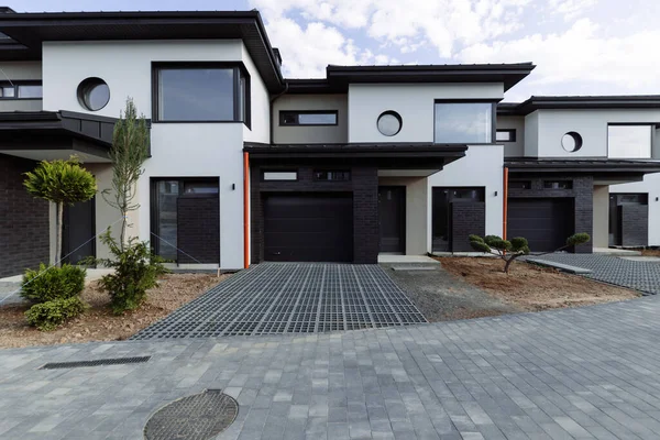 Park ve mavi gökyüzünün arka planında panoramik pencereleri olan birçok modern beyaz kulübe.