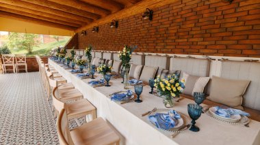 A table is set in a wooden gazebo near a house outside the city. Birthday decor.