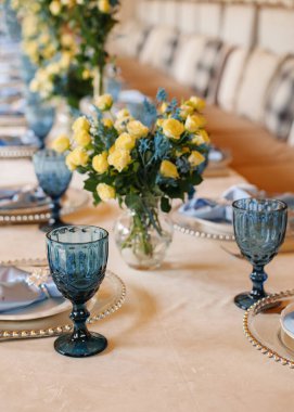 Birthday table decor. Blue glasses and napkins. Flowers on the table.