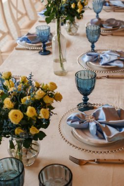 Birthday table decor. Blue glasses and napkins. Flowers on the table.