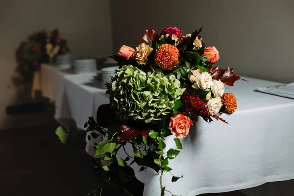 A bouquet of flowers from the side on a table in a restaurant. Festive dinner decor.