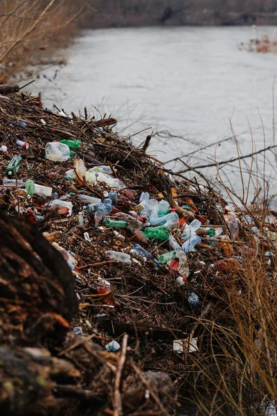 A pile of plastic near the river after the flood. Man pollutes the environment